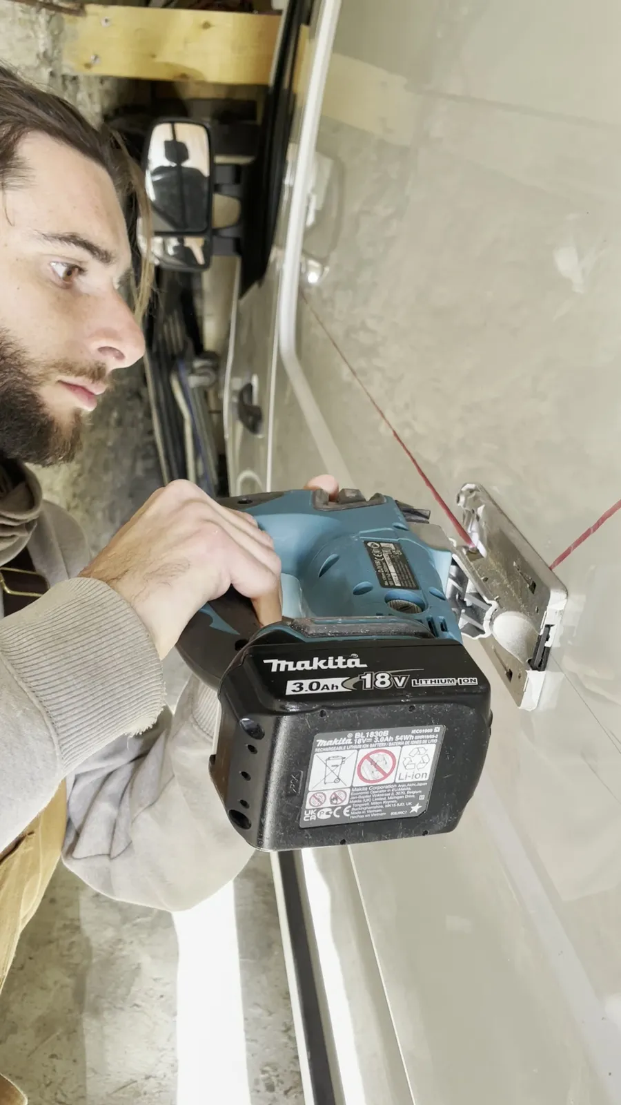 Découpe de la tôle à la scie sauteuse sans fil Makita 18 V, le long du trait rouge, sur l'un de nos fourgons