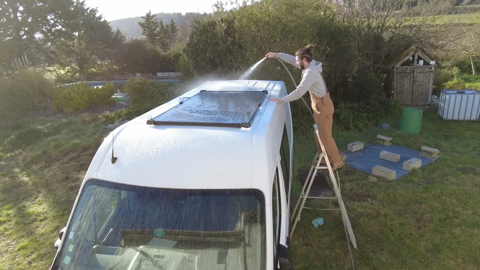 Arrosage du toit depuis un escabeau pour tester l'étanchéité autour du panneau solaire et des passages de toit