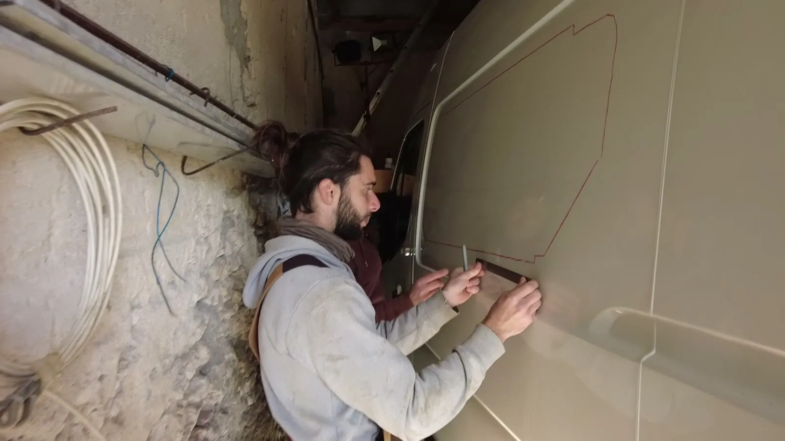 Traçage au marqueur rouge du contour d'une fenêtre latérale sur la tôle d'un de nos fourgons, une équerre posée sur la paroi