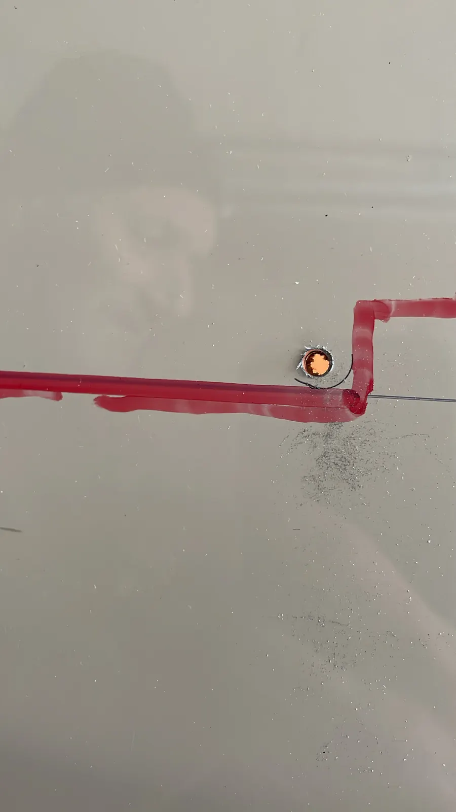 Trou percé dans l'angle d'un tracé rouge sur la tôle blanche d'un fourgon